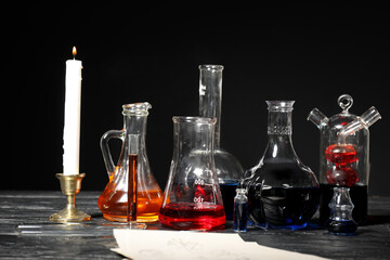 Potions, paper sheets and candle on alchemist's table