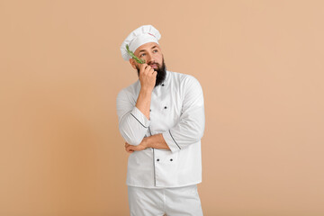 Handsome thoughtful male chef on color background