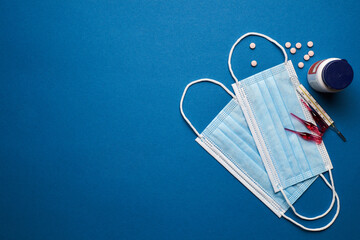 Prevent coronavirus. Medical mask, thermometer, vitamins, syringe on blue background.