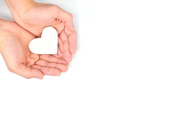 Cupped hands holding a white heart in white background. Charity, pure love, compassion and kindness...