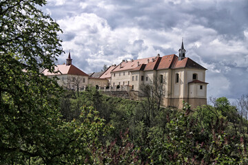 Fototapeta na wymiar Nizbor castle over green trees in day with heavy clouds