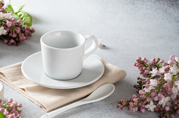 Fototapeta na wymiar empty coffee cup on a light background, near a branch of lilac. 