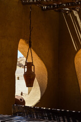 Old clay jar hanging on a rope from the ceiling in the shade near the window inside a desert bedouin home in Sahara desert, Egypt
