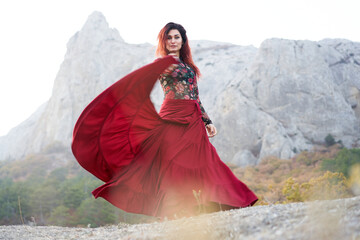 Woman in red long dress dancing on mountains view