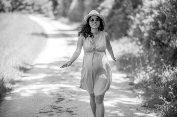 Outdoor portrait of happy pregnant woman with sunglasses and hat - summer time in nature - beautiful moments of family life
