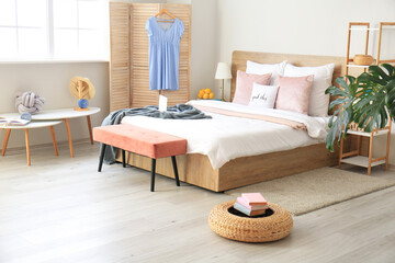 Stylish interior of room with big bed and bench