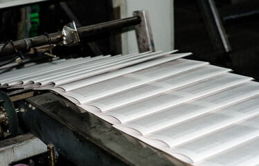 Printing paper Newspapers in the printing house. Printed publications on the industrial conveyor. Publishing house. Latest news release. Fresh press.