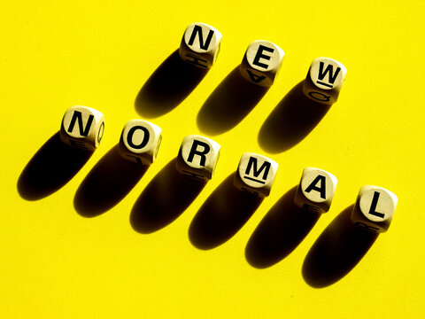 New Normal, word on wooden alphabet cube on yellow background, minimal style.