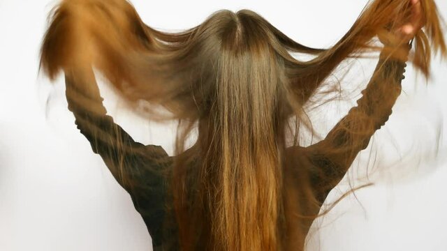 A young beautiful woman straightens her long luxurious hair