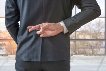 Businessman with his fingers crossed behind his back in the office