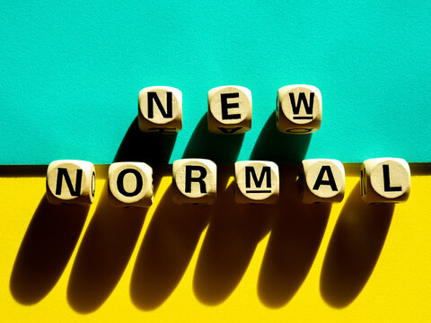 New Normal, word on wooden alphabet cube on light green and yellow background, minimal style.