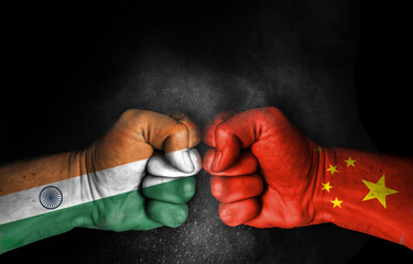 Conflict and tension between India and China, male fists with flags painted on skin isolated on black background - fight and conflict between two countries concept