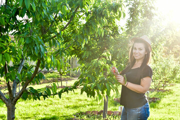 Smiling happy  young  woman gardener in an  organic  orchar apple garden in a sunny day