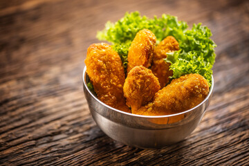 Chicken nuggets with salad in a metal bowl on a rustic wooden surface