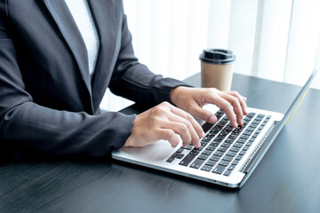 Business woman in a black suit typing laptop, concept working from home