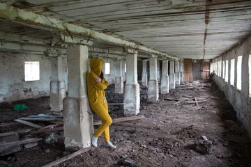 Fototapeten Verlassene Gebäude  A girl in a gloomy abandoned building in a black cloak. Young woman in an industrial abandoned factory  © Natali