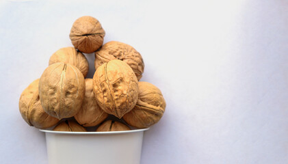 Walnuts in a white plastic cup. Brown hard shell. Daylight. Concept of  store, a healthy diet, vegetarianism.