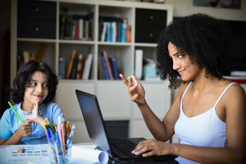 metis woman working home with her son doing his homework