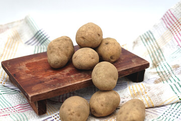 Pile of unpeeled potatoes above wood cutting board
