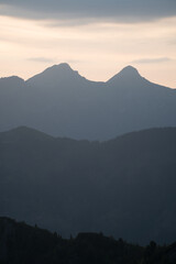 Remarkable sunrise over deep valley, ravine with direct orange sunlight catching flora in front of camera. High mountains very early in the morning illuminated by red light of sun.