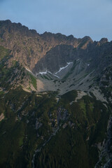 Remarkable sunrise over deep valley, ravine with direct orange sunlight catching flora in front of...