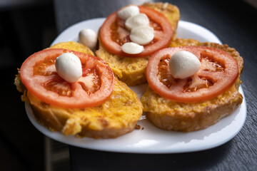 Croutons with fresh tomato and mozzarella on the white plate for breakfast in the morning. Vegetarian meal