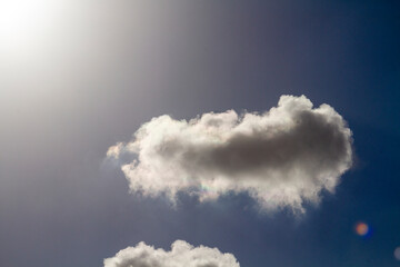 Beautiful puffy clouds in the rays of the sun on a blue sky.