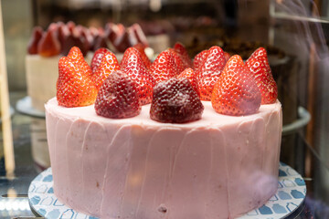 Strawberry-yogurt cake on a bakery sail behind a glass. The temptation to diet