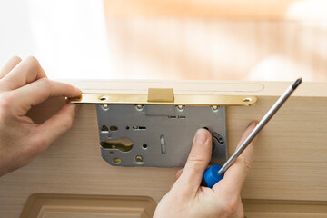 Handyman installing lock in front the wooden interior door.