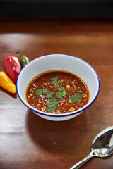 Mexican tomato soup with vegetables, with pepper on wooden table, traditional cuisine concept 
