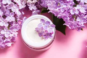 Obraz na płótnie Canvas Jar of natural face cream with lilac flowers on pink background