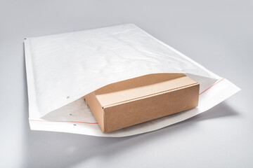 Brown cardboard box packed in white bubble envelopes on grey background