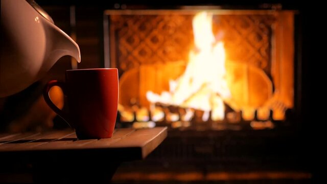 A cup of hot tea near the burning fireplace. Cozy mood. Waiting for the holiday.	