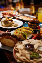 triangle-shaped corn chips with sauces and mexican burritos on table, close view,  mexican traditional cuisine concept on wood table