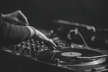 The DJ 's hands play at the club on the turntables. disco. night life. atmosphere. black-and-white...