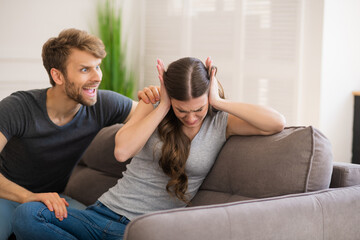 Young bearded man shouting on his wife while she closing her ears