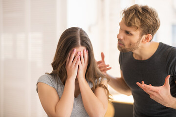 Young long-haired woman closing her face while her husband shouting