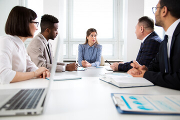 Obraz premium International group of business people working and communicating sitting near office desk.