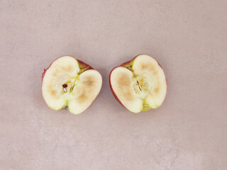 halved tainted red apple isolated on pale pink background