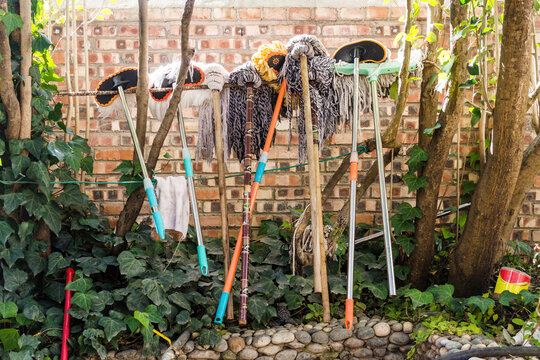 Brooms And Mops Hanging In A Garden Outdoor