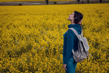 Woman traveler in a flowering rapeseed field.