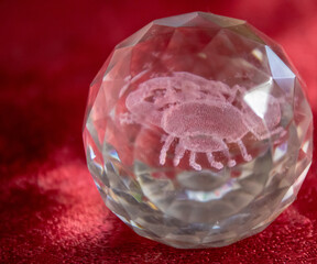 A glass egg with iridescent faces and inside the zodiac sign Scorpio.