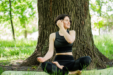 A short-cut slender smiling caucasian girl enjoys doing yoga ardha-padmasana half lotus pose. 
