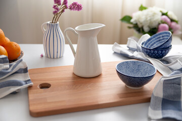 The bowl is placed on a wooden cutting board next to some white and blue textiles. Greek blue, flowers, and pure style.