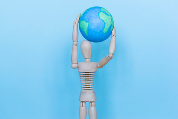 Ecology concept, wooden man and globe on the blue background.