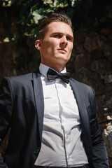 Happy man, groom in elegant suit coat outdoors during wedding photosession. Photography with stylish husband on a summer sunny day, love and family concept.