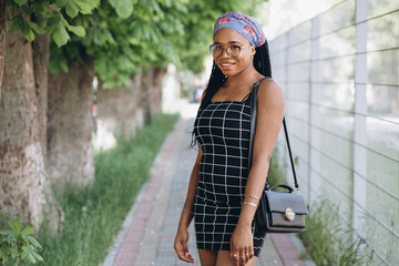 Beautiful young african woman wearing fashionable dress posing on the street. Fashion look photo. Afro hairstyle