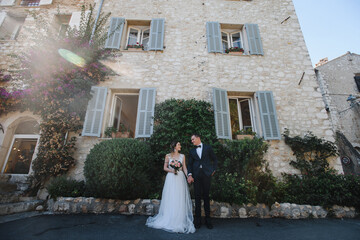 Beautiful wedding couple outdoor portrait. Photography with young pretty bride with groom on natural background near stony building at wedding photosession. Just married, love and family concept.