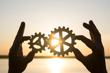 a man holds gears in his hands against the background of the sunset