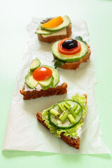 Row of vegetarian sandwiches on green background. Selective focus.